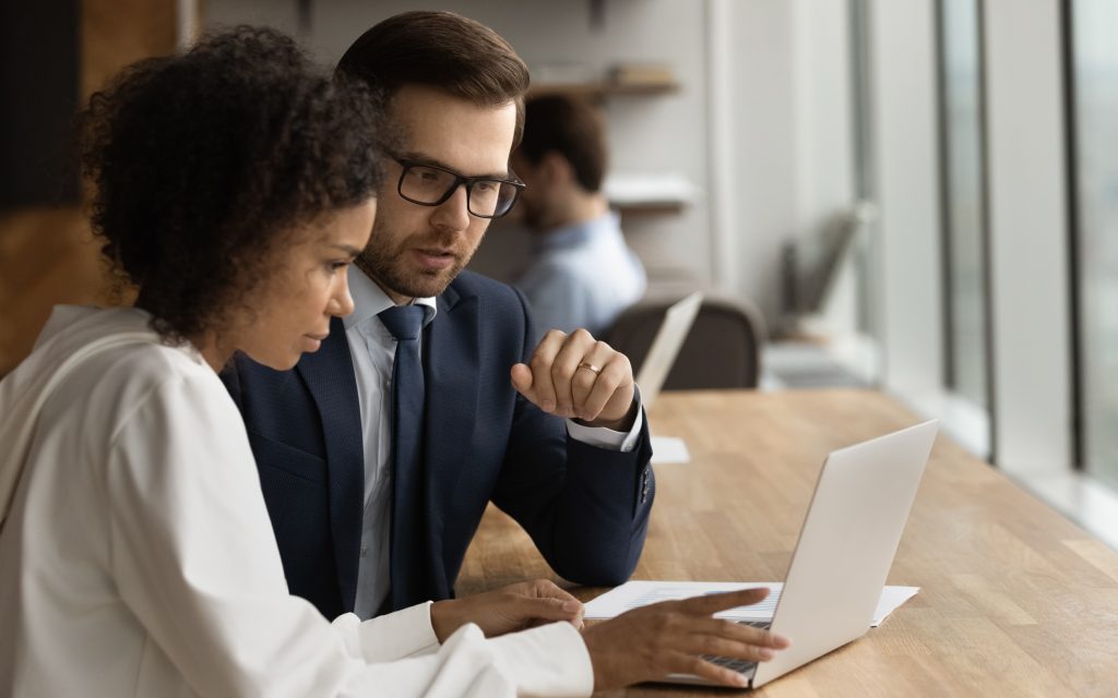 Two people looking at a laptop together in an office.
